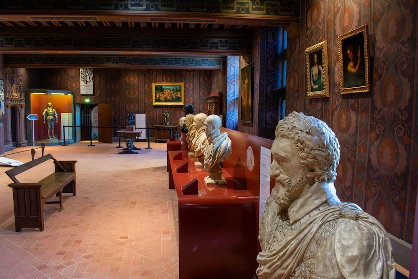 A museum interior with marble busts, wooden benches, and patterned walls. 2