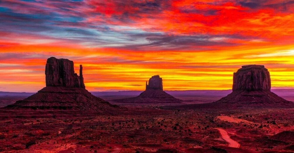 A desert landscape with three prominent rock formations under a vibrant sunset sky. 3