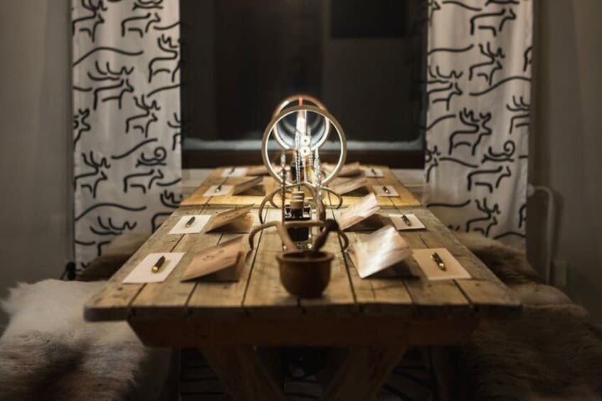 A wooden table with a vintage radio and papers, set against a window with patterned curtains. 2