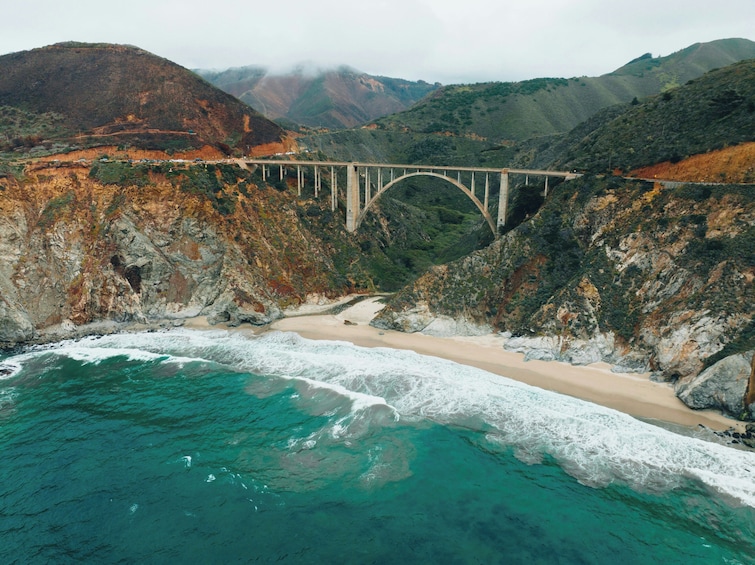 Un paysage côtier avec un pont, une plage et un relief montagneux. 3