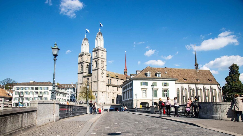 A historic bridge with a prominent church tower and a red spire, surrounded by traditional European architecture. 1