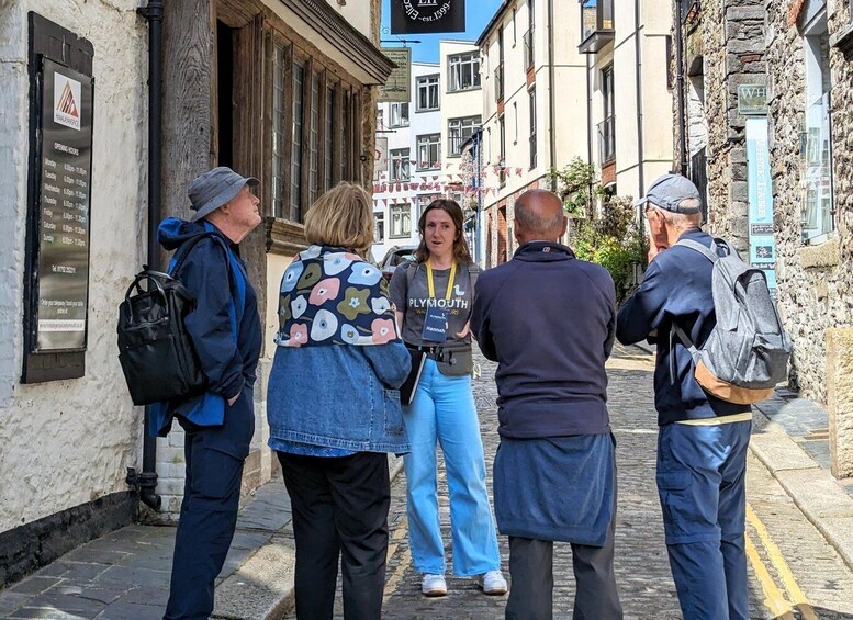 A group of people standing on a cobblestone street, looking at a signboard. 3