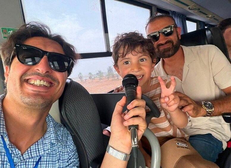 Three people on a bus, one holding a microphone. 3