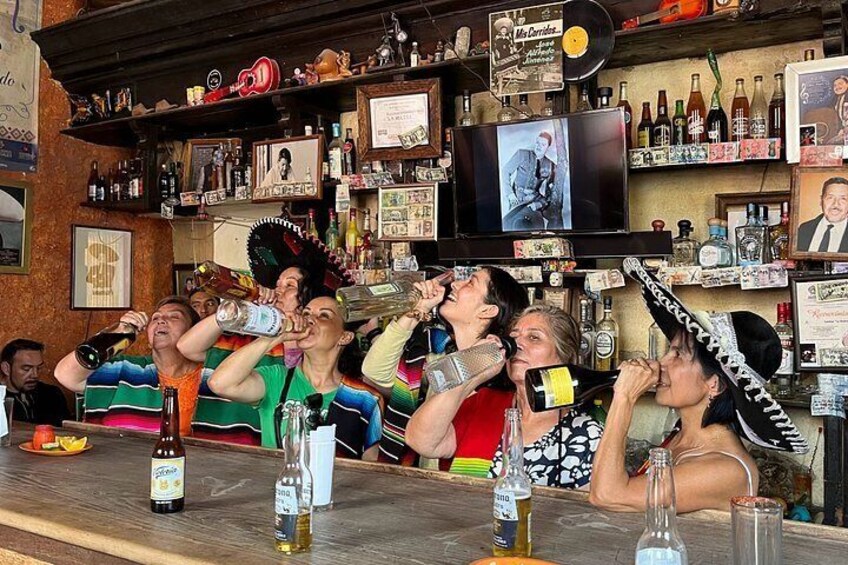 A bar with people drinking and a television displaying a movie. 1