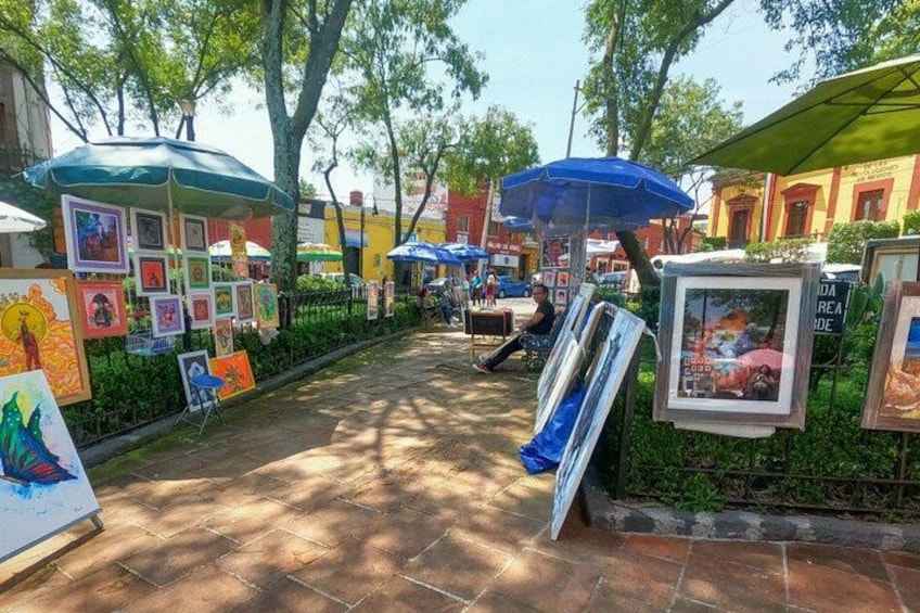 An outdoor art display with paintings and umbrellas. 3