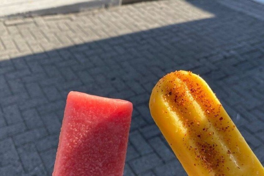 Two ice cream bars, one red and one yellow, on a tiled surface. 4