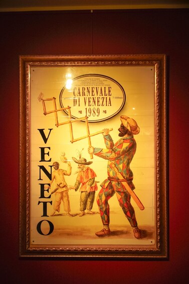 A framed poster with a carnival scene, including a character in a colorful costume and a sign reading 'CARNEVALE DI VENEZIA 1989.' 2