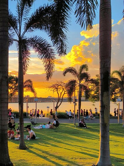 A park with people sitting and walking during sunset. 2