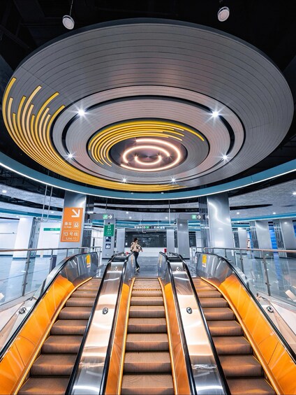 An indoor escalator with a circular ceiling design and directional signs. 4