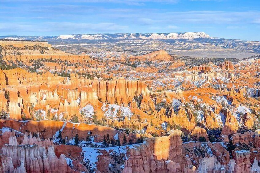 Un extenso paisaje de cañón con formaciones rocosas rojas y parches de nieve. 2