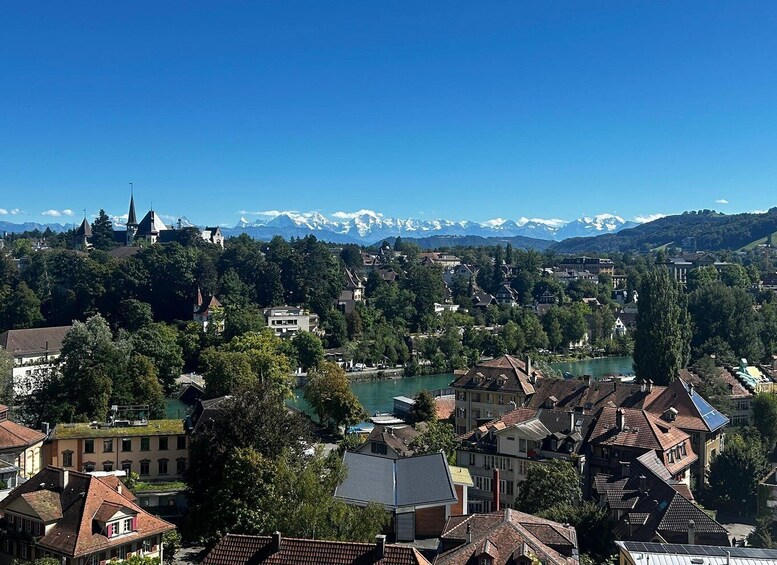 A town with a river, houses, and snow-capped mountains in the background. 3