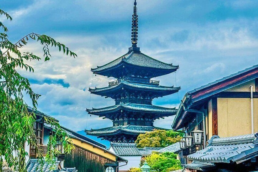 Une pagode japonaise traditionnelle à plusieurs étages, entourée de bâtiments aux toits couverts de tuiles et de verdure. 3