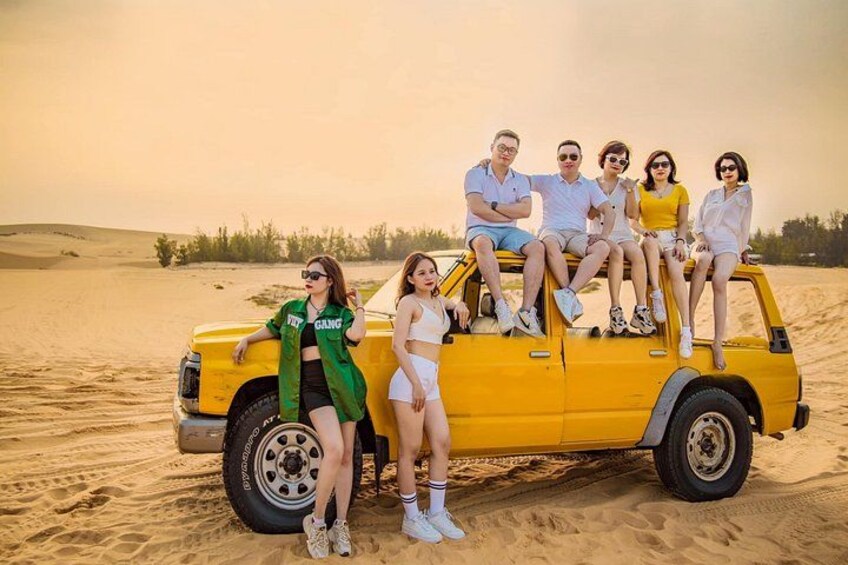 A group of people on a yellow vehicle in a desert. 5