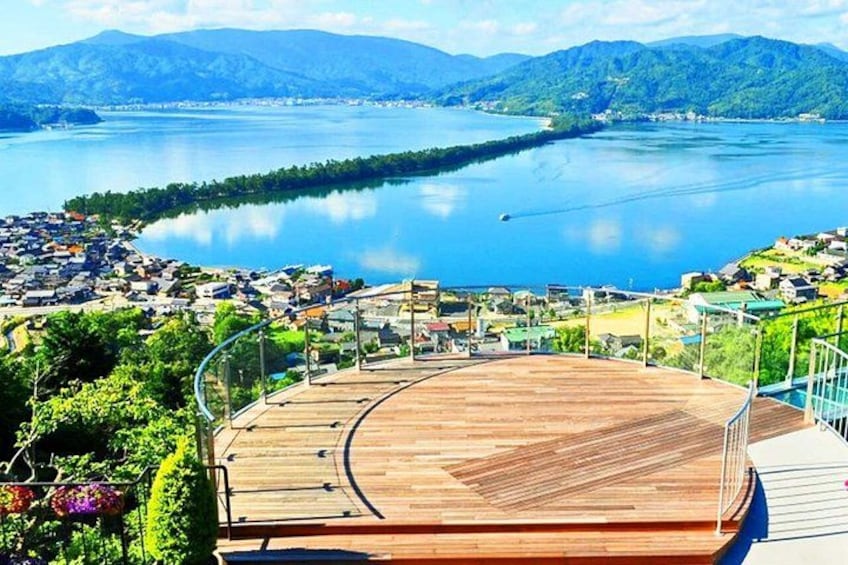 A wooden deck overlooking a lake with a town in the background. 1