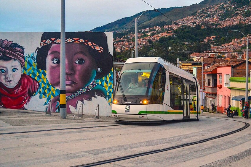 A tram on tracks with a mural in the background. 1