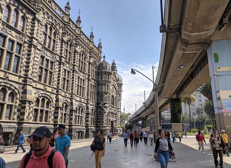 A busy urban street with historic architecture and a modern elevated train track. 5