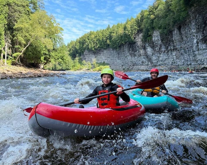 Two people kayaking on a river surrounded by cliffs. 3