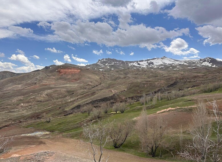 A mountainous landscape with snow-capped peaks, a clear sky, and sparse vegetation. 3