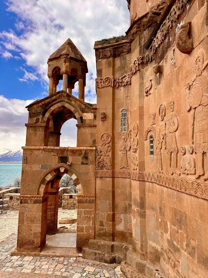 An ancient stone structure with an arched entrance, detailed carvings, and a bell tower. 1