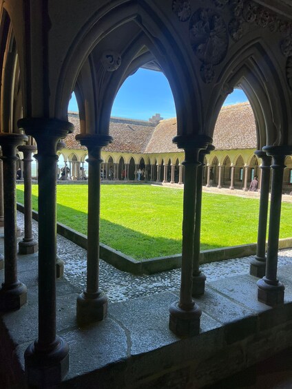 An interior courtyard with arches and columns, a green lawn, and a view of a building with a tiled roof. 3
