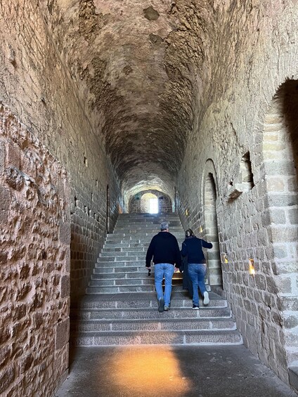 A stone staircase in a tunnel with two people walking up. 5