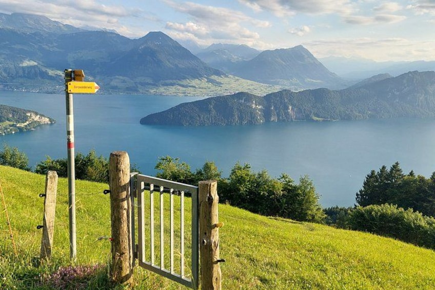 A mountain landscape with a lake, a wooden gate, and a directional sign. 3