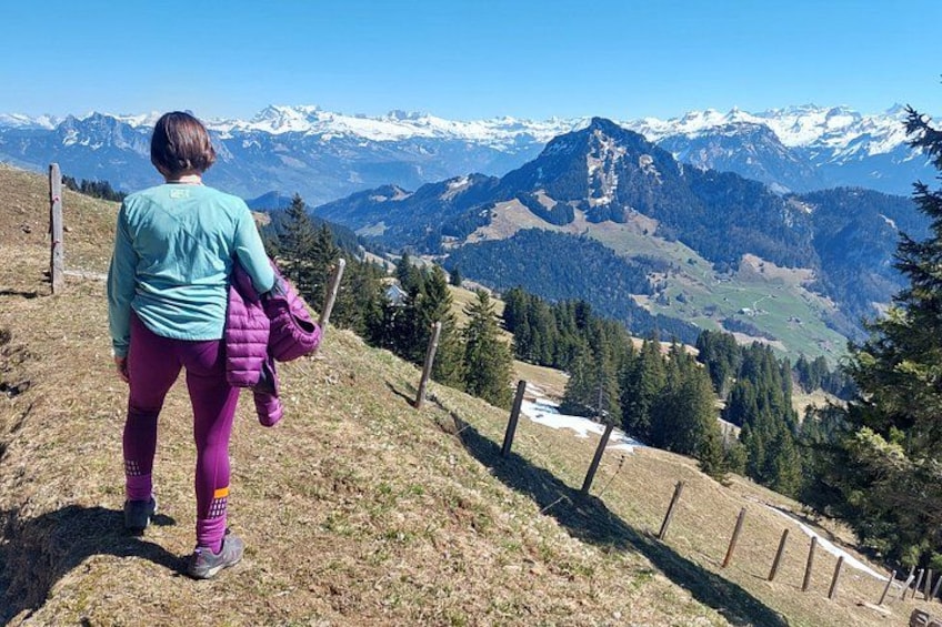 A person standing on a grassy hill with a mountainous landscape in the background. 2