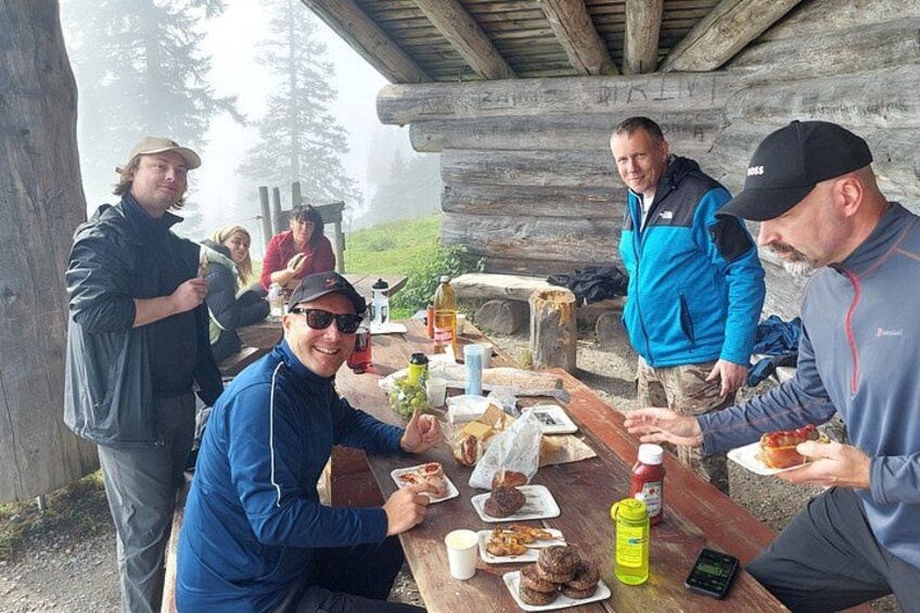 A group of people dining outdoors at a wooden table with food and drinks. 4