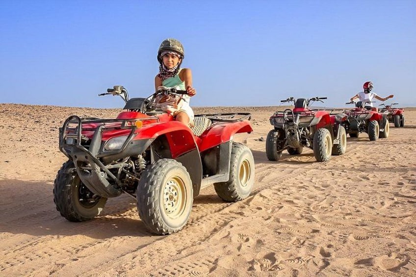 A desert landscape with four red off-road vehicles parked on the sand. 1