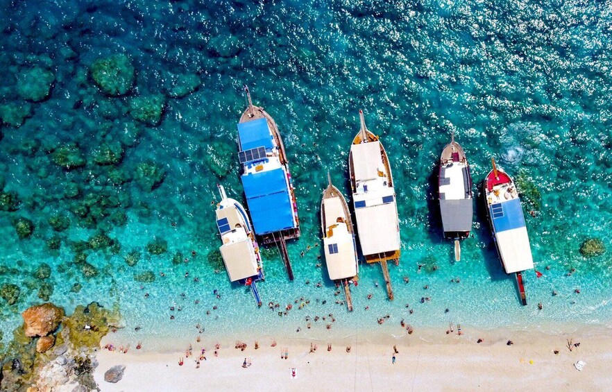 A clear turquoise sea with boats anchored near the shore. 1