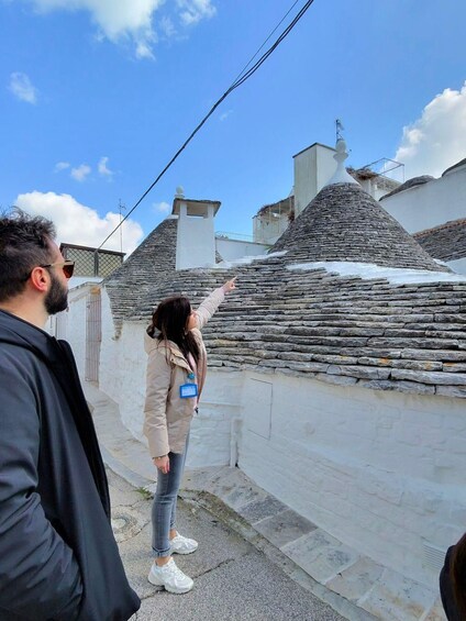 A person pointing at a stone wall with a snow-covered roof. 2
