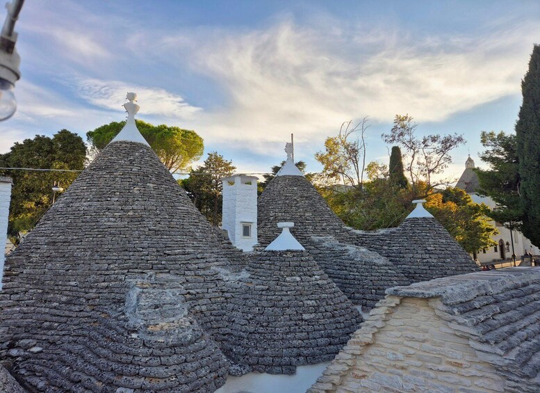 Traditional stone huts with conical roofs, a stone pathway, and a church in the background. 5