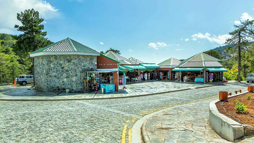 A cobblestone street with shops and a stone kiosk. 4