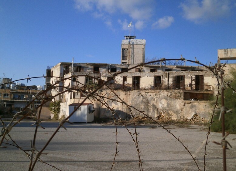 A dilapidated building with barbed wire in the foreground. 3
