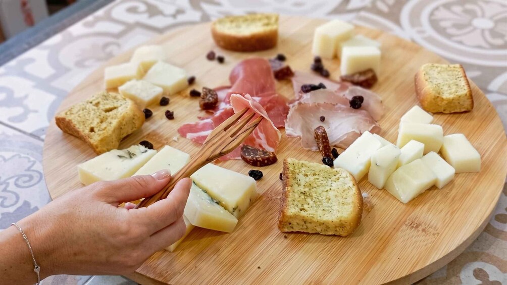 A wooden board with various cheeses, cured meats, and bread. 1