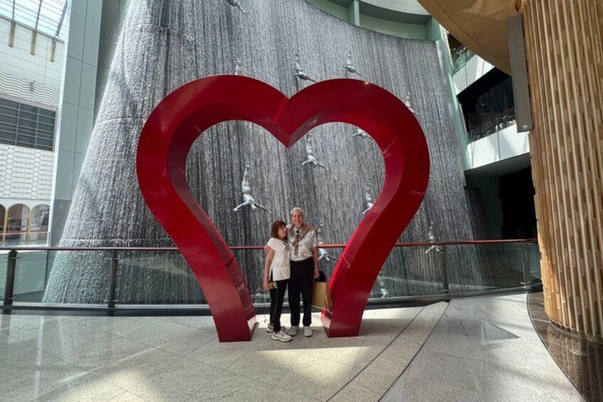 Una gran escultura de corazón rojo en un espacio público interior con un fondo arquitectónico moderno. 3