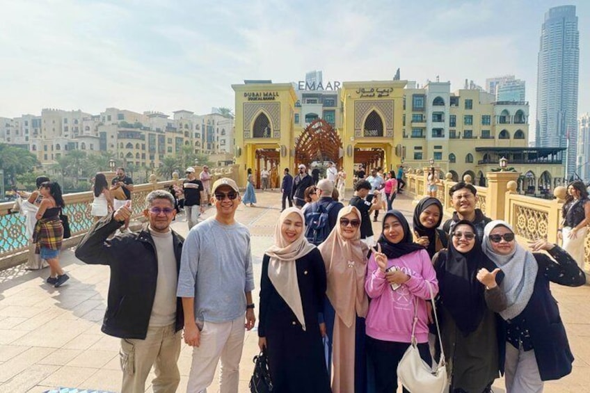 Eine Gruppe von Menschen posiert vor der Dubai Mall und den Gebäuden von Emaar. 2