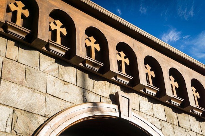 Une façade d’immeuble ornée de nombreuses fenêtres en arc, chacune contenant un symbole en forme de croix. 3