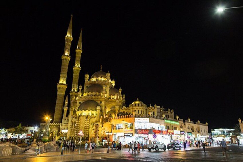 A large mosque with multiple minarets and domes, illuminated at night. 5