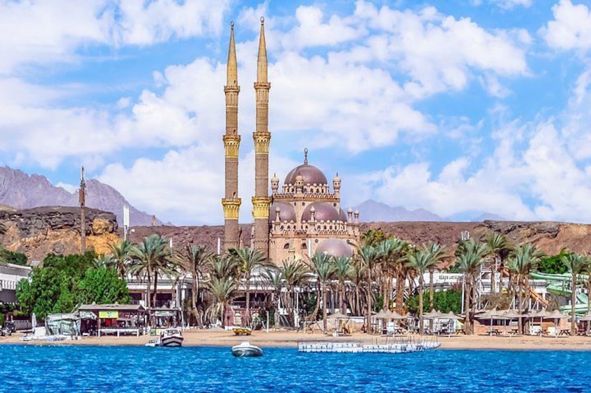 Une mosquée dotée de deux minarets, de palmiers et bordée d’un plan d’eau. 5