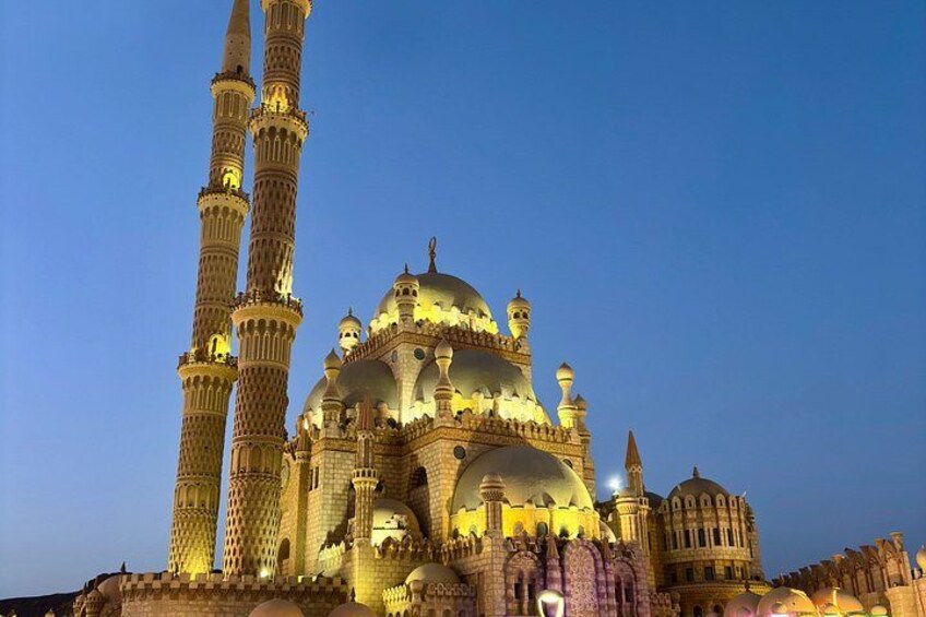 A grand mosque with multiple domes and minarets, illuminated at dusk. 3