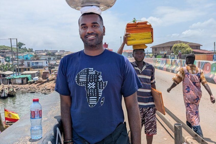 A man carrying a large load on his head, another man walking with a load on his head, and a third person walking in the background. 3