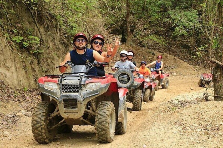 Des personnes conduisent des quads sur un chemin de terre, entouré d’arbres. 3
