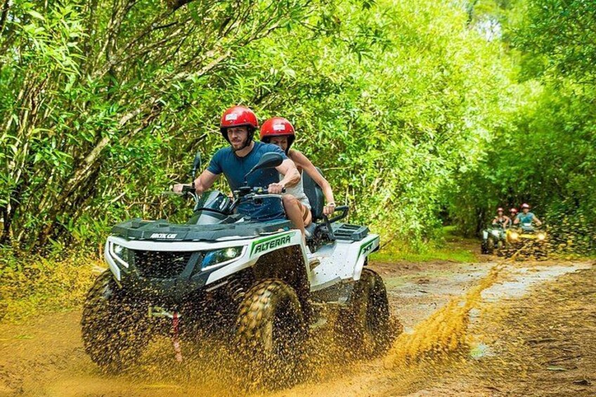 Une personne conduit un véhicule tout-terrain sur un chemin boueux, entourée d’une végétation luxuriante. 5