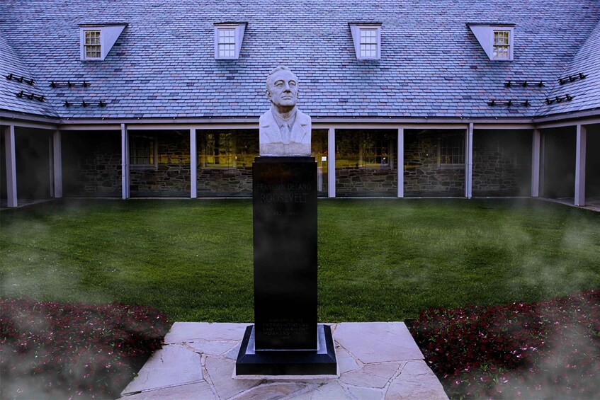 A statue of Franklin Delano Roosevelt in a courtyard with a stone building in the background. 5