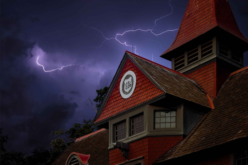 A red-roofed building with a circular emblem and lightning in the sky. 1