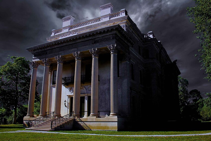 A neoclassical building with columns and a portico, surrounded by a well-maintained lawn and trees. 3