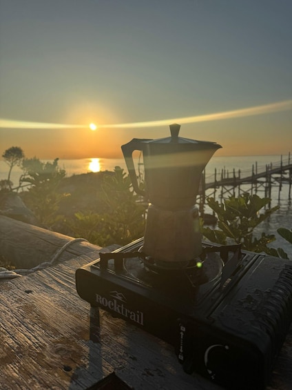 A coffee maker on a wooden surface with a sunset in the background. 4