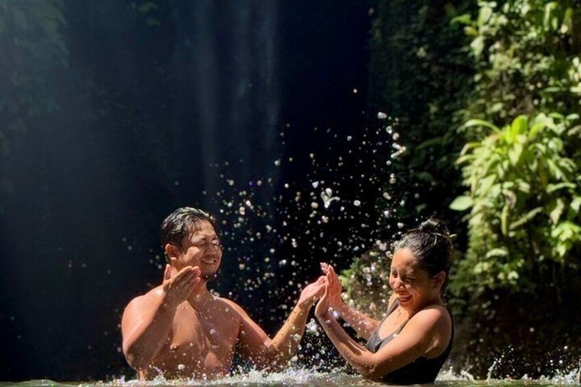 Dos personas en un cuerpo de agua, rodeadas de vegetación y salpicaduras. 5