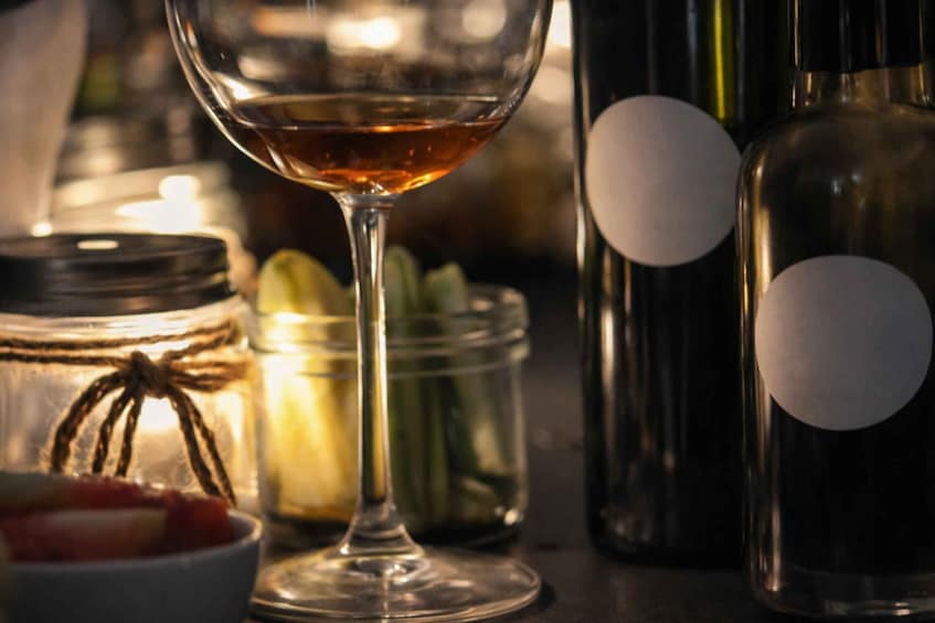 A wine glass, jars, and bottles on a table. 1